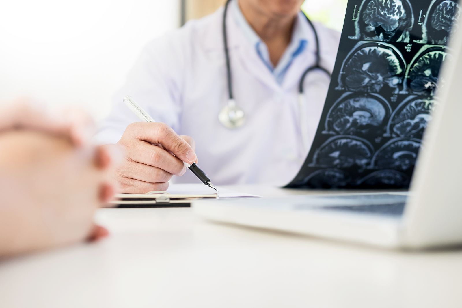 How Personal Injury Attorneys Prove Long-Term Effects in Brain Injury Cases, Professor Doctor discussion a method with patient treatment with Mammogram film x-ray of patient 's head for brain skull or eye injury and laptop computer on table.