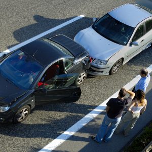 Auto Accident Attorney for car accident, three people stand by the roadside discussing what has happened after a small shunt on the freeway (motorway autoroute autobahn).